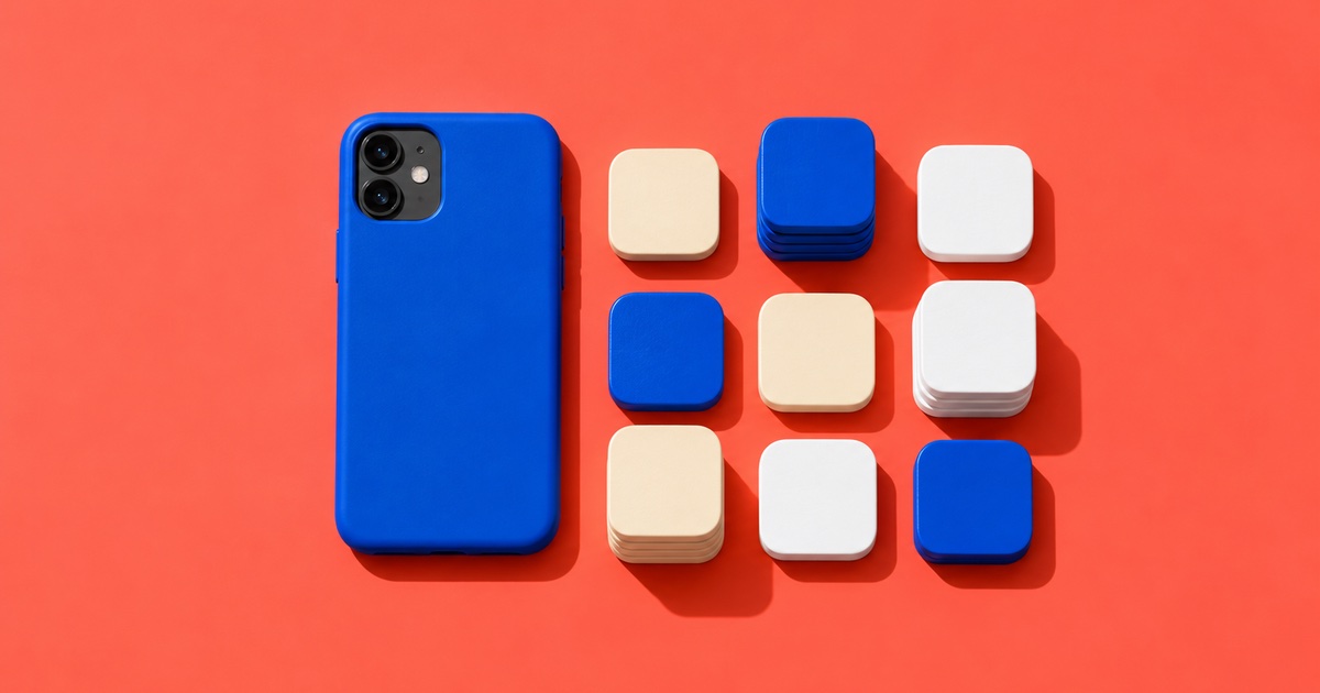 A phone in a blue case lying face-down beside blank cream, blue and white app-icon tiles on a coral background